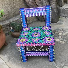 a colorfully painted chair sitting in front of a potted plant