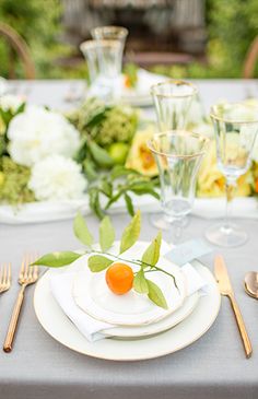 an image of a table setting with oranges and white flowers on the place settings