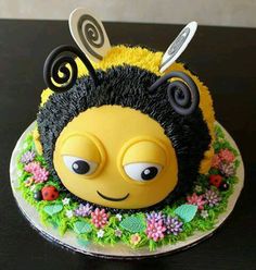 a cake decorated to look like a bee with flowers and leaves on it's head