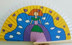 a hand holding up a colorful fan with a mermaid on it's head and clouds in the background