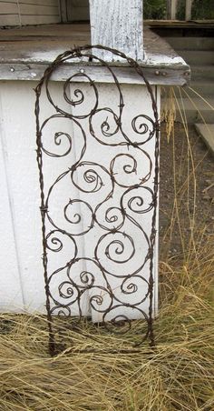 an iron gate sitting in the grass next to a white building with a red sign that says pint