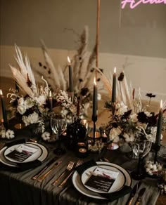 the table is set with black and white place settings, silverware, pamonini, flowers, and candles