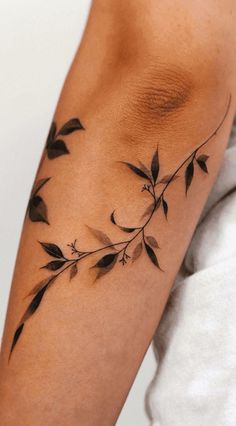 a woman's arm with black leaves on it