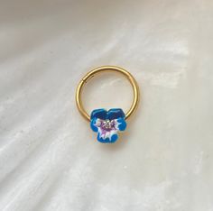 a gold ring with blue and white flowers on the outside, sitting on a white sheet