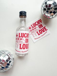 a bottle of lucky in love next to disco ball and mirror balls on the table