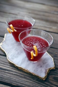 two glasses filled with liquid sitting on top of a tray