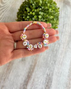 a hand holding a beaded bracelet with letters on it