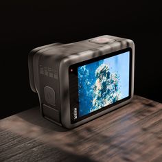 a digital camera sitting on top of a wooden table next to a black wall and floor