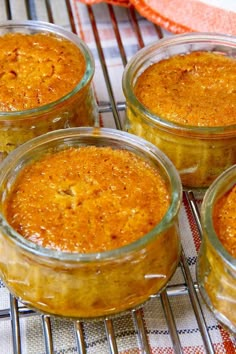 four glass jars filled with food sitting on top of a metal cooling grating rack