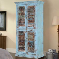 an old blue armoire with glass doors in a bedroom next to a nightstand and lamp