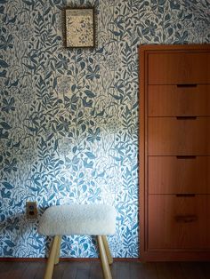 a white bench sitting in front of a wall with blue and white designs on it