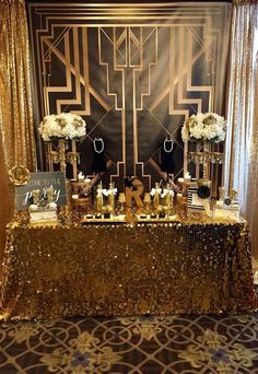 the table is set up with gold sequins and white flowers, candles, and decorations