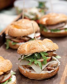 sandwiches with meat, lettuce and cheese on a wooden platter lined up