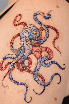 an octopus tattoo on the back of a woman's upper body, with blue and red ink