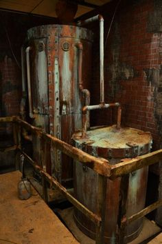 an old machine is sitting in the middle of a room with brick walls and exposed pipes