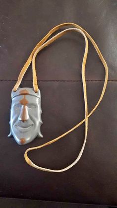 a leather bag with a silver mask on it's side and a yellow cord hanging from the strap