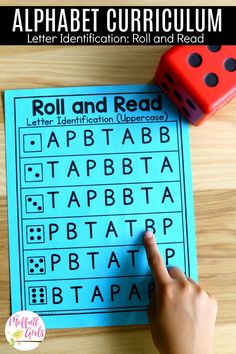 a hand pointing at a roll and read game on a wooden table with a red dice