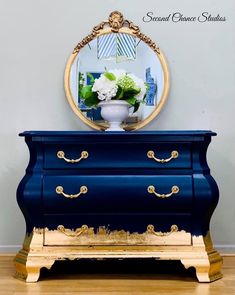 a blue dresser with gold trim and flowers on top