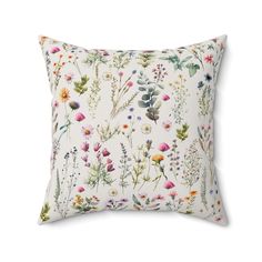 a white pillow with colorful flowers and plants printed on the front, sitting on a white background