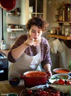 a woman standing in front of a table filled with tomatoes and other food items on it