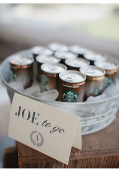 a glass bowl filled with lots of drinks on top of a wooden table next to a sign that says joe to go