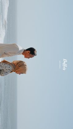 a man and woman standing next to each other near the ocean