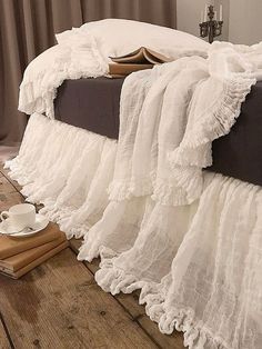 a bed with ruffled bedspread and pillows on it next to a cup of coffee