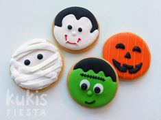 three decorated cookies with faces on them and one in the shape of a ghost, jack - o'- lantern