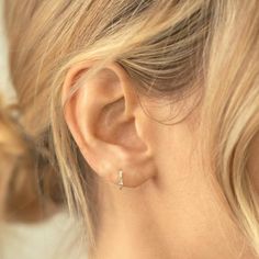 a close up of a woman's ear wearing an ear cuff with two small crosses on it