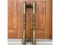 two ornate brass candlesticks are standing in front of a wooden door with tile flooring