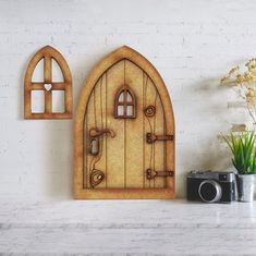 a white brick wall with a wooden door and two windows on the side, next to a camera