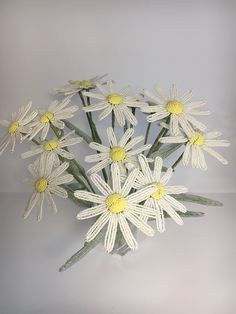 a vase filled with white and yellow flowers on top of a table next to a wall