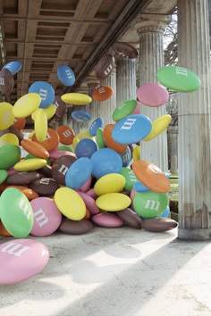 many balloons are floating in the air under a bridge with columns and pillars behind them