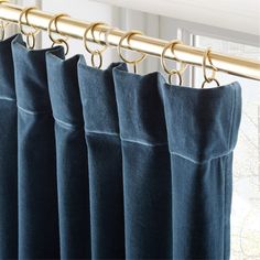 blue curtains hanging on a gold rod in front of a window with windowsills