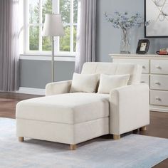 a white chair sitting on top of a rug in a living room next to a window