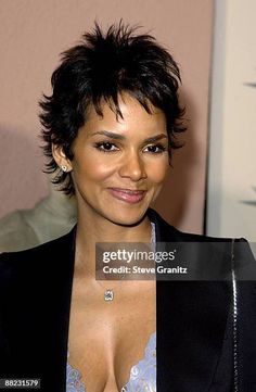 a woman in a black jacket and bra top posing for the camera with her hand on her hip