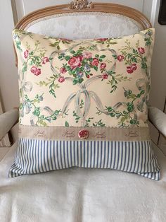 a decorative pillow is sitting on a white chair with a striped pillow and blue stripped pillow