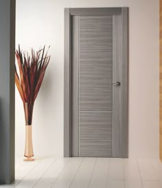 an empty room with a door and vase on the floor next to it, in front of a white wall