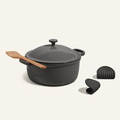 a black pot with wooden spoons next to it