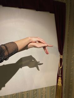 a woman's hand reaching out to touch something on the wall in front of her