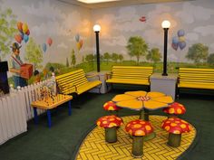 a brightly colored room with yellow benches and colorful decorations on the walls, along with tables and chairs