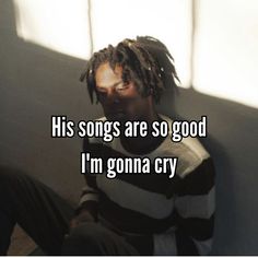 a man with dreadlocks sitting against a wall