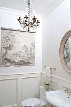 a white toilet sitting next to a sink under a chandelier