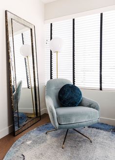 a blue chair sitting in front of a large mirror