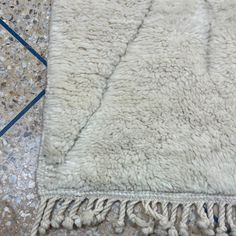 a white rug with tassels laying on the floor next to a tile floor