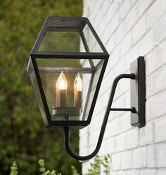 two lit candles are attached to an outdoor wall light