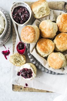 scones with jam and butter on a plate next to two bowls of cream cheese