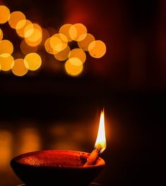 a lit candle sitting on top of a wooden table next to a blurry background