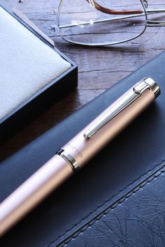 a pen sitting on top of a desk next to a pair of eyeglasses