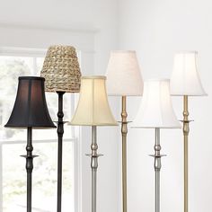 four lamps are lined up next to each other on the floor in front of a window